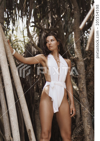 Tropical Beauty Shot of Beach Woman Model in Stylish White Modern Swimwear in the Jungle 105554598