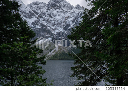 Morskie Oko lake Snowy Mountain Hut in Polish Tatry mountains, Zakopane, Poland. Beautiful green hills and mountains in dark clouds and reflection on the lake Morskie Oko lake 105555534