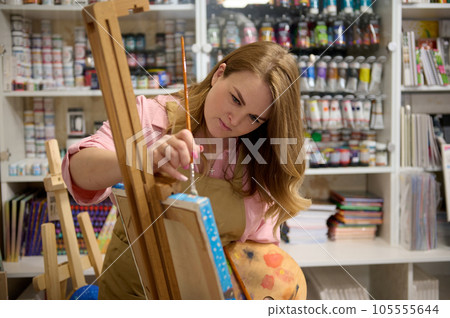 Inspired female artist painting on canvas in her art studio, searching for imagination. Creative hobby and occupation 105555644