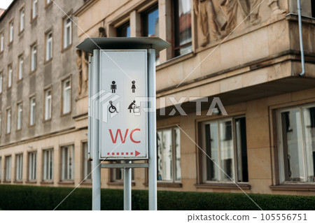 WC logo, sign of public toilets in the street against building background. For female, male and disabled people. 105556751