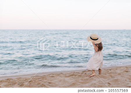 Little girl in a straw hat on the beach by the sea, back view 105557569
