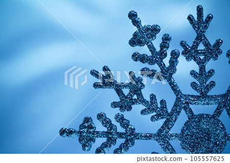 Macro shiny snowflake on blue blurred background. Merry Christmas card. Copy space 105557625