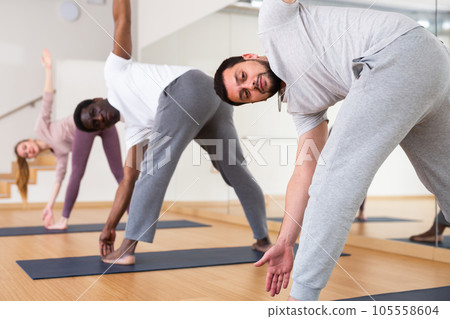 Men and woman doing windmill exercise in gym Men and woman doing windmill exercise in gym 105558604