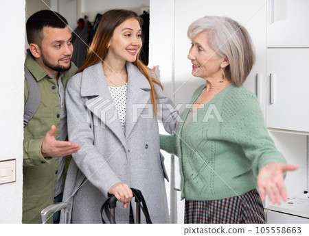 Senior woman welcoming couple at home 105558663