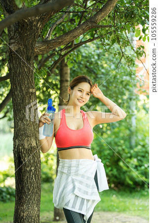 a young woman wearing summer morning sportswear and carrying a water bottle a young woman wearing summer morning sportswear and carrying a water bottle 105559286