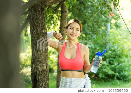 a young woman wearing summer morning sportswear and carrying a water bottle 105559460