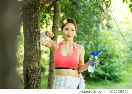 a young woman wearing summer morning sportswear and carrying a water bottle 105559461