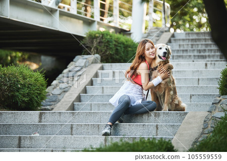 In the park, a lovely dog and a beautiful woman in sportswear are exercising together. 105559559
