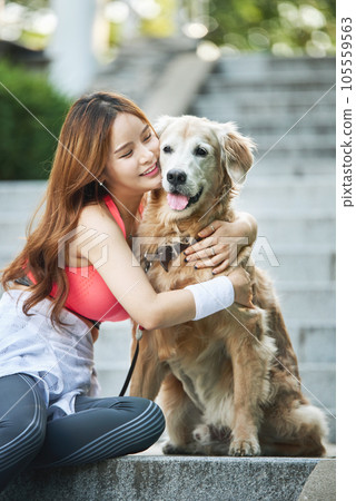 In the park, a lovely dog and a beautiful woman in sportswear are exercising together. 105559563