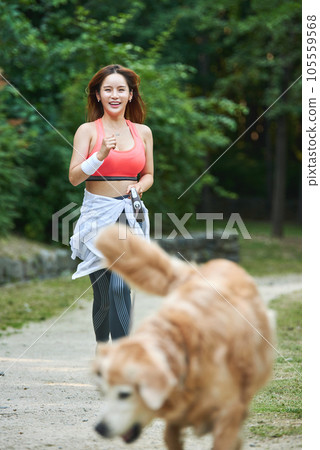 In the park, a lovely dog and a beautiful woman in sportswear are exercising together. 105559568