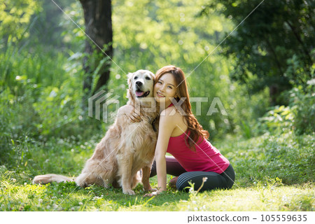In the park, a lovely dog and a beautiful woman in sportswear are exercising together. 105559635
