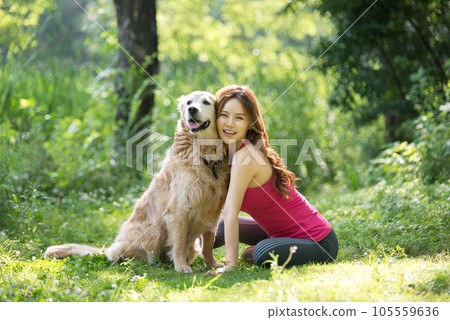 In the park, a lovely dog and a beautiful woman in sportswear are exercising together. 105559636