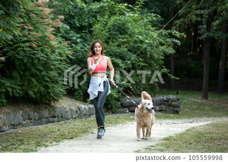 In the park, a lovely dog and a beautiful woman in sportswear are exercising together. In the park, a lovely dog and a beautiful woman in sportswear are exercising together. 105559998