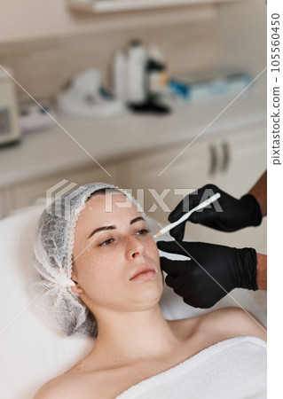 cosmetologist marking skin of caucasian woman with pencil. cosmetologist marking skin of caucasian woman with pencil. 105560450