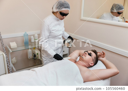 young man undergoes procedure of arm pit laser epilation young man undergoes procedure of arm pit laser epilation 105560460