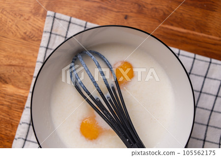 Organic homemade eggs in a bowl with kefir or milk. Cooking. Whisk in female hands. High quality photo Organic homemade eggs in a bowl with kefir or milk. Cooking. Whisk in female hands. High quality photo 105562175