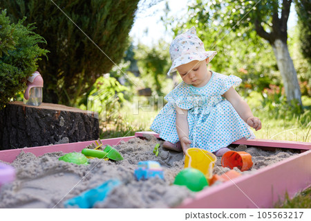 baby girl playing in sand on outdoor playground 105563217