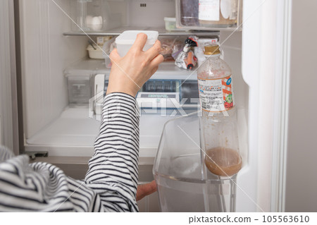 [A housewife taking out a tapper from the refrigerator] 105563610