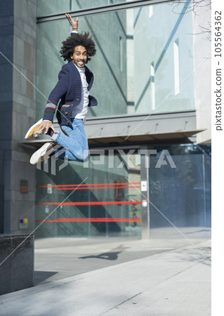 Happy young African American man jumping in the street. 105564362