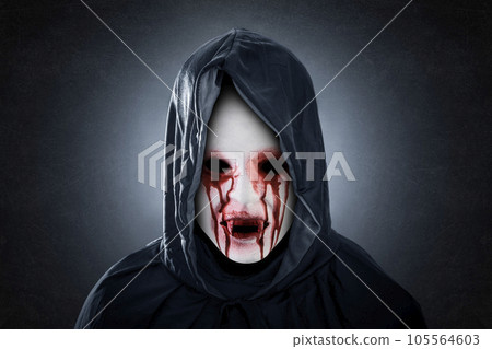 Creepy bloody vampire with hooded cape over dark misty background 105564603