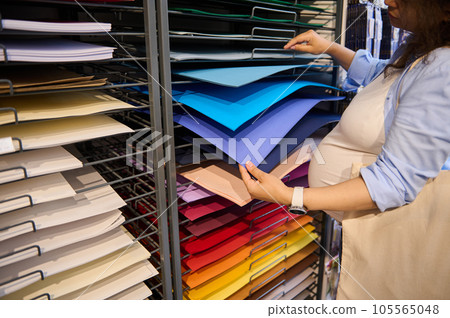 Multicolored cardboard sheets or design paper of vibrant spectrum in artist designer's hands selecting paper in art shop Multicolored cardboard sheets or design paper of vibrant spectrum in artist designer's hands selecting paper in art shop 105565048
