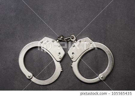 The metal handcuffs on black background. Handcuff or shackle. Police handcuffs The metal handcuffs on black background. Handcuff or shackle. Police handcuffs 105565435