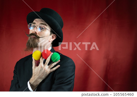 Vintage Caucasian Magician with top hat, glasses and mustache with colored balls 105565460