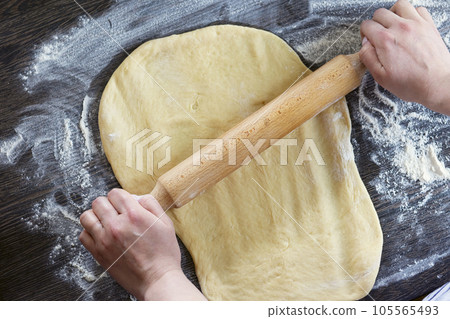 Hands, rolling-pin and dough for bread, pasta or pizza on wooden table Hands, rolling-pin and dough for bread, pasta or pizza on wooden table 105565493
