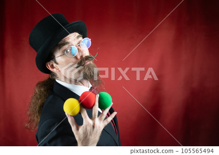 Vintage Caucasian Magician with top hat, glasses and mustache with colored balls 105565494