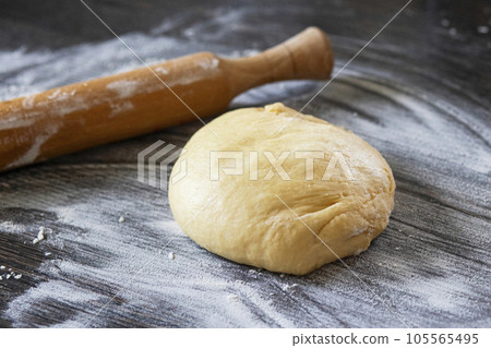 Fresh dough ready to bake. Bread dough on wooden kitchen counter with rollingpin 105565495