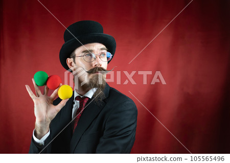 Vintage Caucasian Magician with top hat, glasses and mustache with colored balls Vintage Caucasian Magician with top hat, glasses and mustache with colored balls 105565496