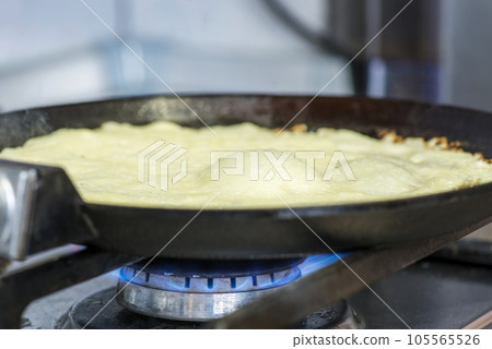The process of cooking pancakes on a hot frying pan on gas stove range The process of cooking pancakes on a hot frying pan on gas stove range 105565526