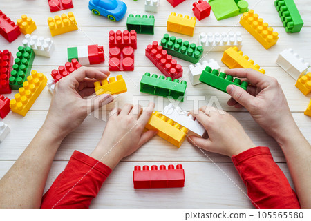 Top view on childs and fathers hands playing with colorful plastic bricks. 105565580
