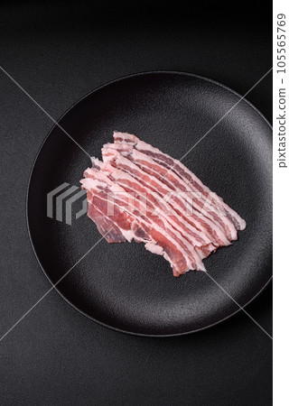 Fresh raw bacon cut into slices with salt, spices and herbs Fresh raw bacon cut into slices with salt, spices and herbs 105565769