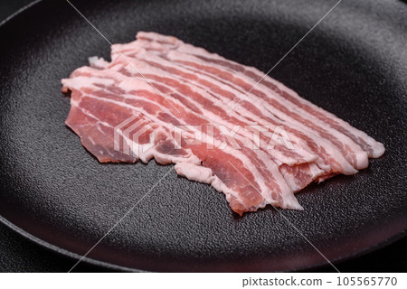 Fresh raw bacon cut into slices with salt, spices and herbs Fresh raw bacon cut into slices with salt, spices and herbs 105565770