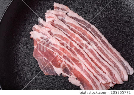 Fresh raw bacon cut into slices with salt, spices and herbs Fresh raw bacon cut into slices with salt, spices and herbs 105565771