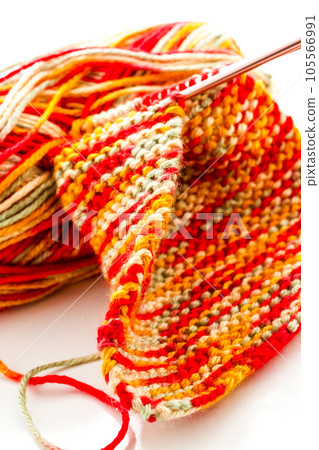 Knitting with multi colored yarn with orange, red, and yellow tones. 105566991