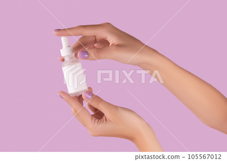Womans hand holding dropper with serum on pastel lavender background 105567012