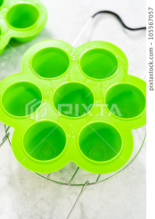 Filling silicone molds with egg mixture to make egg bites in a pressure cooker. 105567057