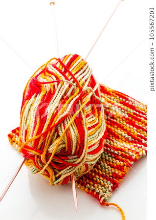 Knitting with multi colored yarn with orange, red, and yellow tones. Knitting with multi colored yarn with orange, red, and yellow tones. 105567201