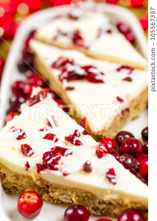 Cranberry bliss bar made with chunks of white chocolate and dried cranberries, topped with sweet cream cheese icing. 105567387