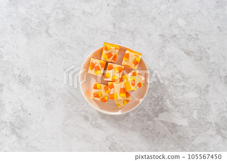 Flat lay. Homemade candy corn fudge square pieces on a white plate. Flat lay. Homemade candy corn fudge square pieces on a white plate. 105567450