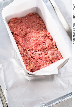 Preparing classic meatloaf in a loaf pan lined with parchment paper. Preparing classic meatloaf in a loaf pan lined with parchment paper. 105567524