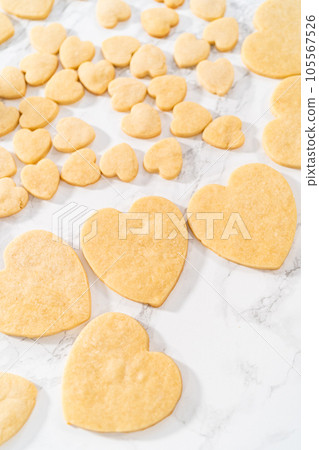 Decorating heart-shaped sugar cookies with pink and white royal icing for Valentine's Day. Decorating heart-shaped sugar cookies with pink and white royal icing for Valentine's Day. 105567526