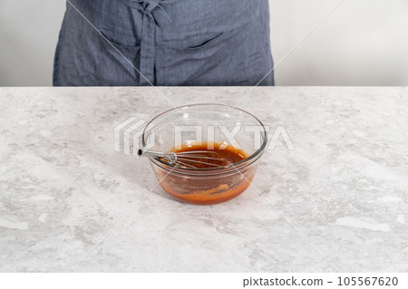 Mixing ingredients with a hand whisk to make a sweet glaze for meatloaf. 105567620
