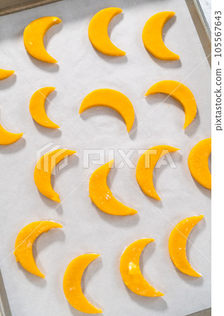 Lemon wedge cookies with lemon glaze. Rolling cookie dough with an adjustable rolling pin and cutting out cookies with cookie cutters to bake lemon wedge cookies with lemon glaze. 105567643