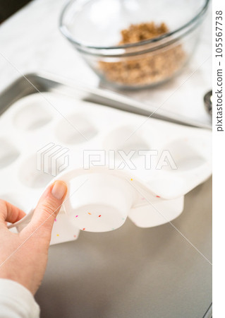 Scooping dough with dough scoop into cupcake pan lined with tulip paper muffin liners to bake banana oatmeal muffins. Scooping dough with dough scoop into cupcake pan lined with tulip paper muffin liners to bake banana oatmeal muffins. 105567738