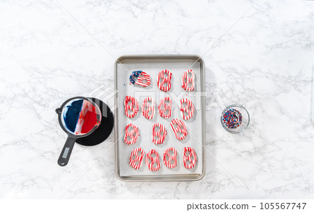Flat lay. Dipping pretzels twists into melted chocolate to make red, white, and blue chocolate-covered pretzel twists. Flat lay. Dipping pretzels twists into melted chocolate to make red, white, and blue chocolate-covered pretzel twists. 105567747