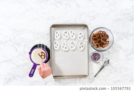 Flat lay. Dipping pretzels twists into melted chocolate to make red, white, and blue chocolate-covered pretzel twists. Flat lay. Dipping pretzels twists into melted chocolate to make red, white, and blue chocolate-covered pretzel twists. 105567791