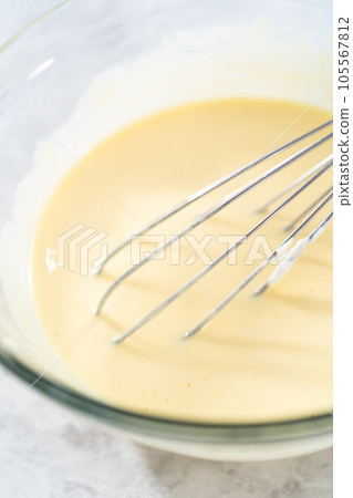 Mixing ingredients in a glass mixing bowl to bake funfettti bundt cake. 105567812